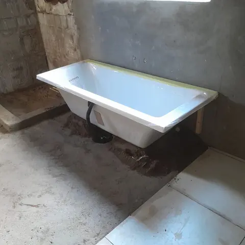 Freestanding bathtub being installed and fitted, still wrapped in protective film