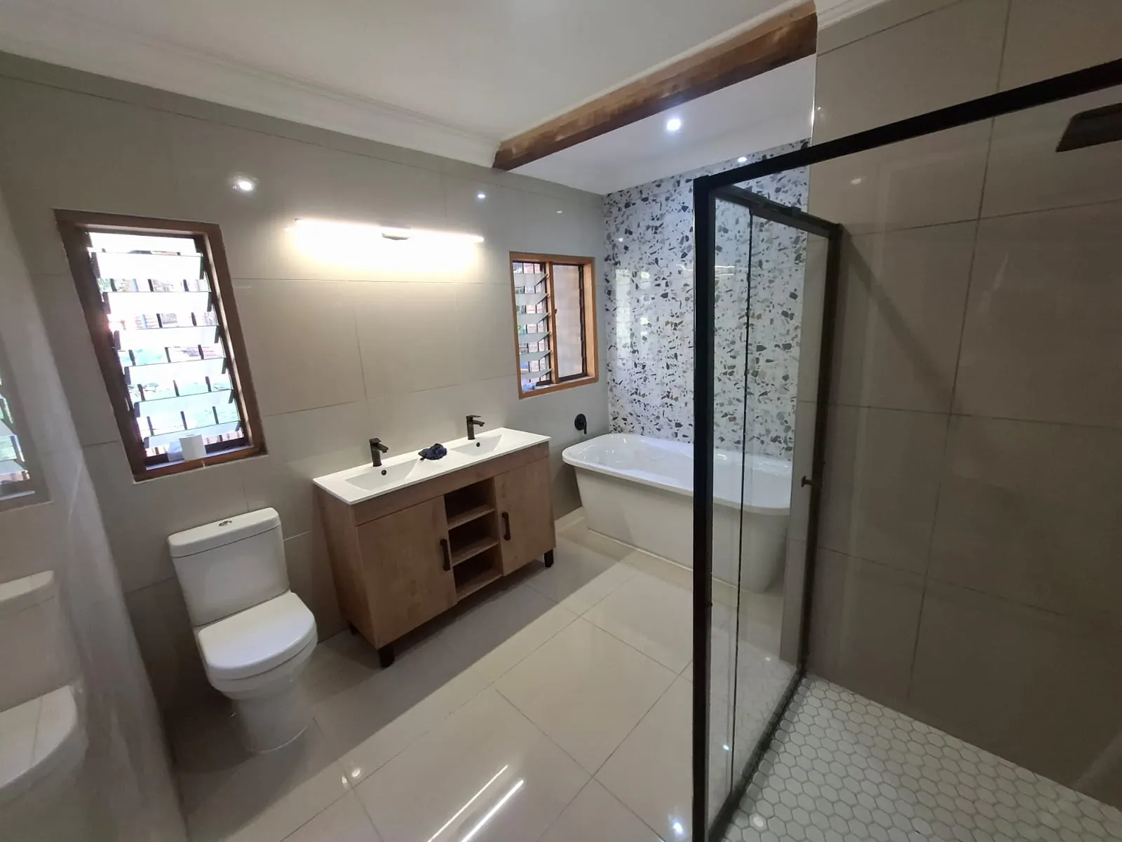 Finished premium bathroom in a Pretoria East home with a freestanding tub, terrazzo tile and recessed lighting, wired and plumbed by Hebert Electrical and Plumbing
