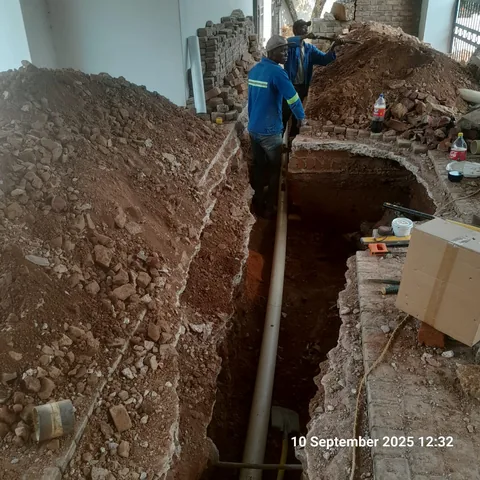 Contractors installing underground conduit in a deep trench at a Pretoria East job site