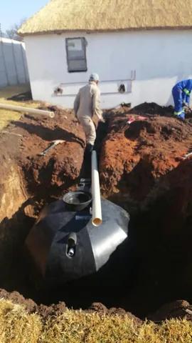 Team placing a large storage tank in an excavated pit beside a thatched Pretoria East home