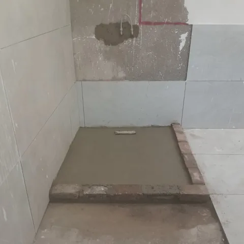 Shower base being formed in wet cement with electrical wiring roughed into the back wall